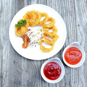 a white plate topped with onion rings and ketchup