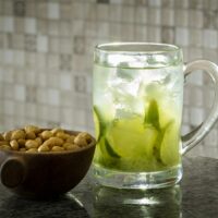 a glass of tea with a green drink and nuts in it