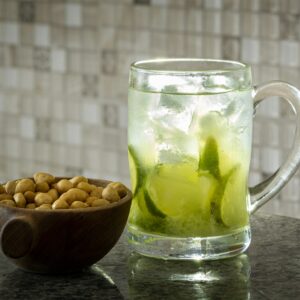 a glass of tea with a green drink and nuts in it