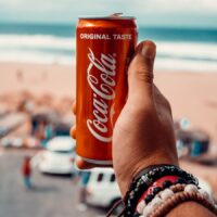 a person holding up a can of coca cola